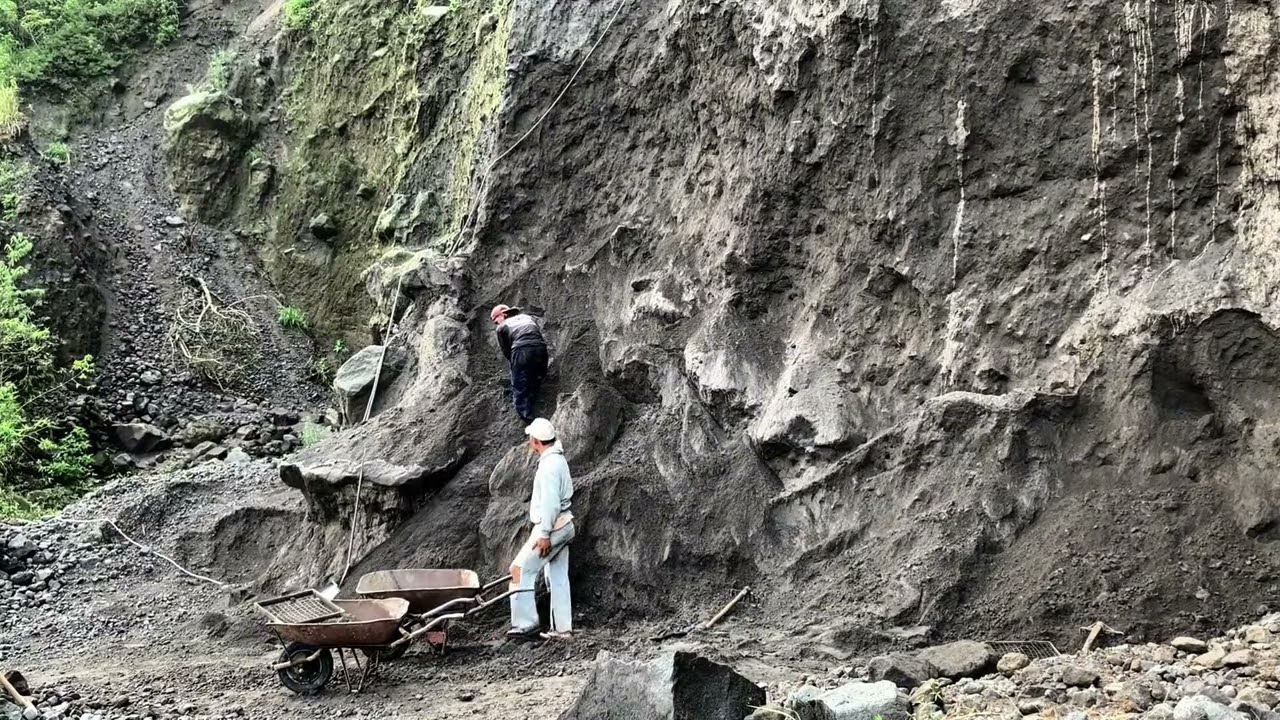 mijnwerkers verzamelen en graven zwart zand onder hoge kliffen