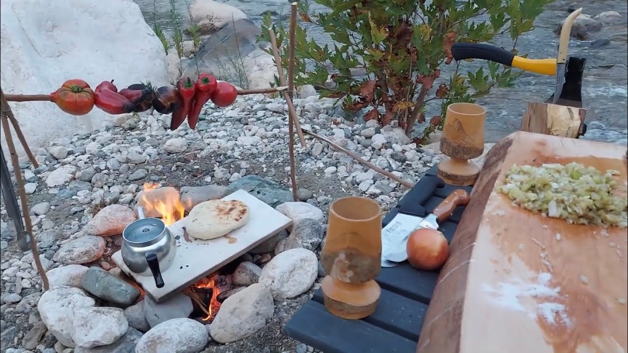 Camping and cooking carp fish by the river in the wild