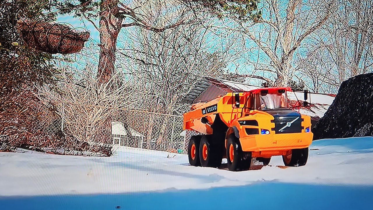 Rc huina Volvo dump truck carrying dirt through snow.