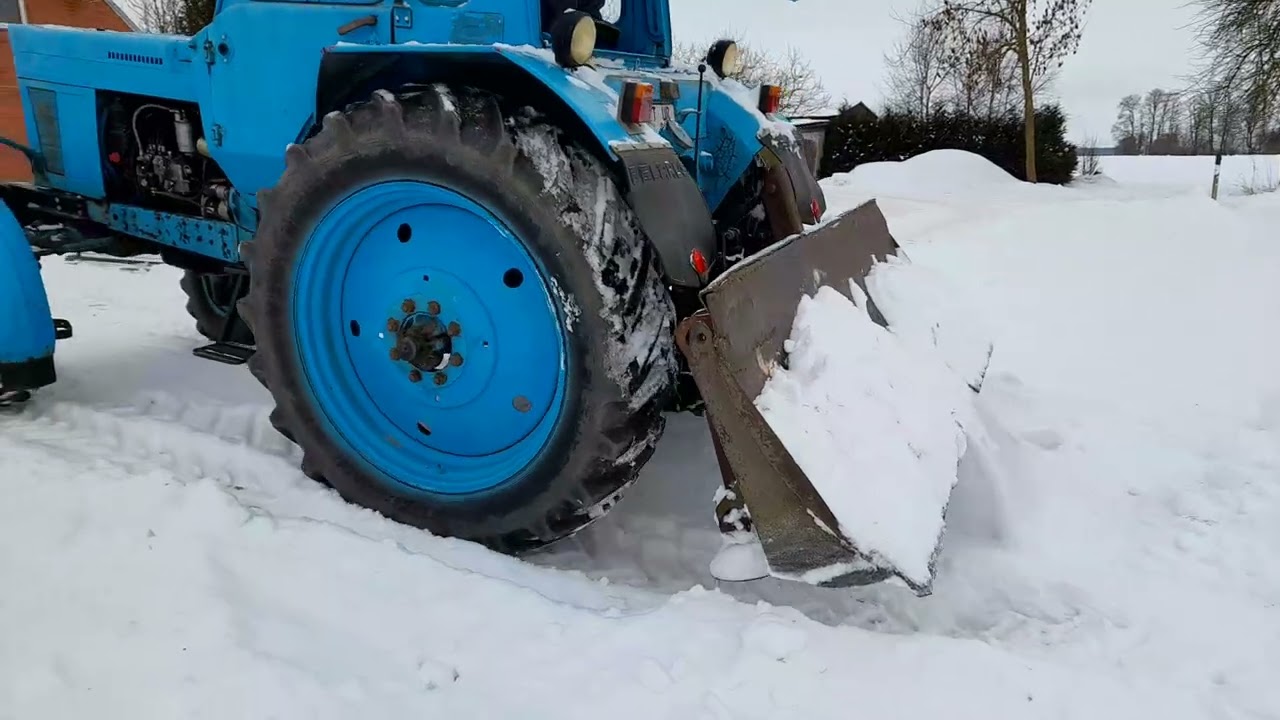 Трактор МТЗ-82 толкает снег.