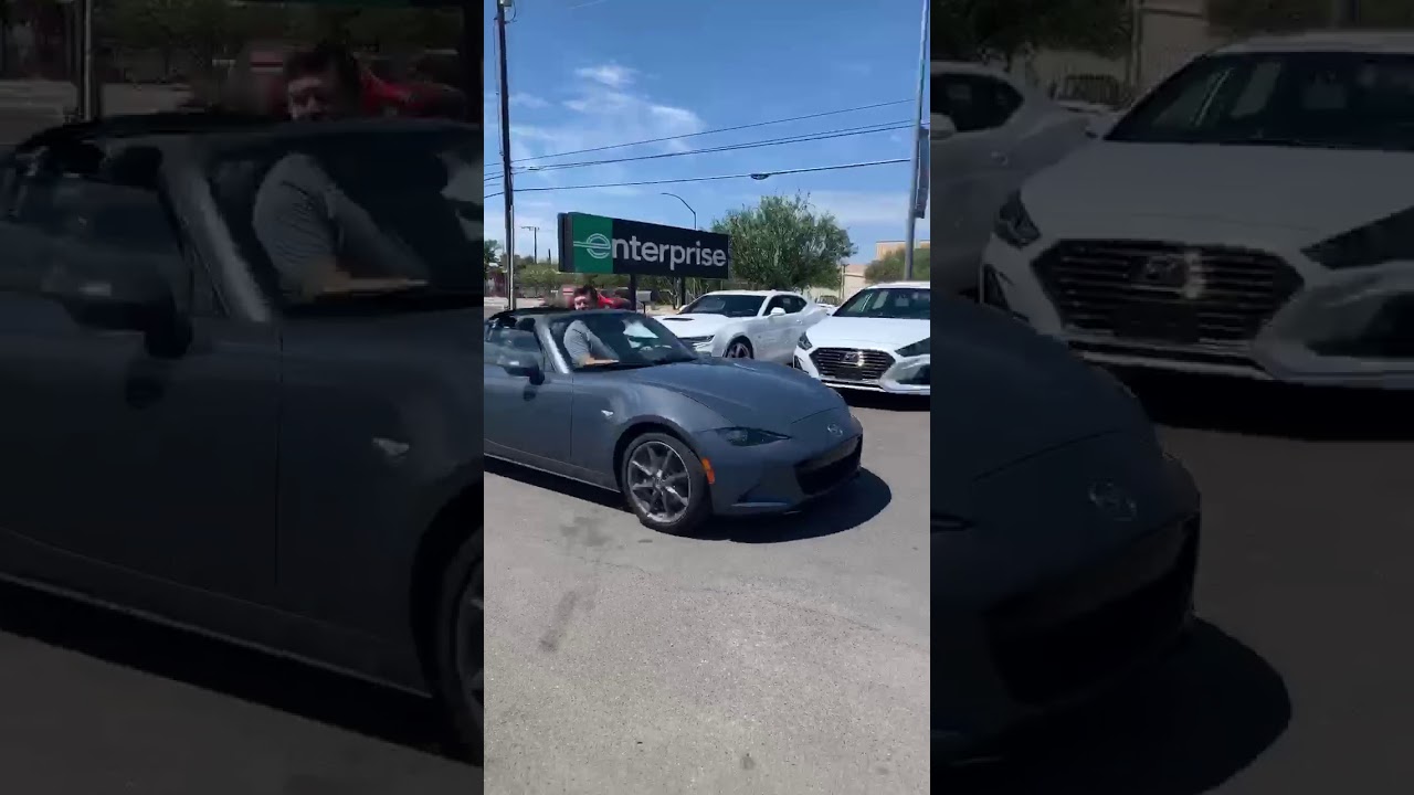 Super tall guy driving convertible and his head is taller than the windshield.