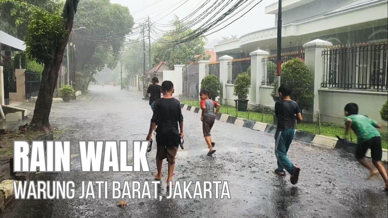 Berjalan di tengah hujan deras kota Jakarta, ditemani anak-anak bermain hujan