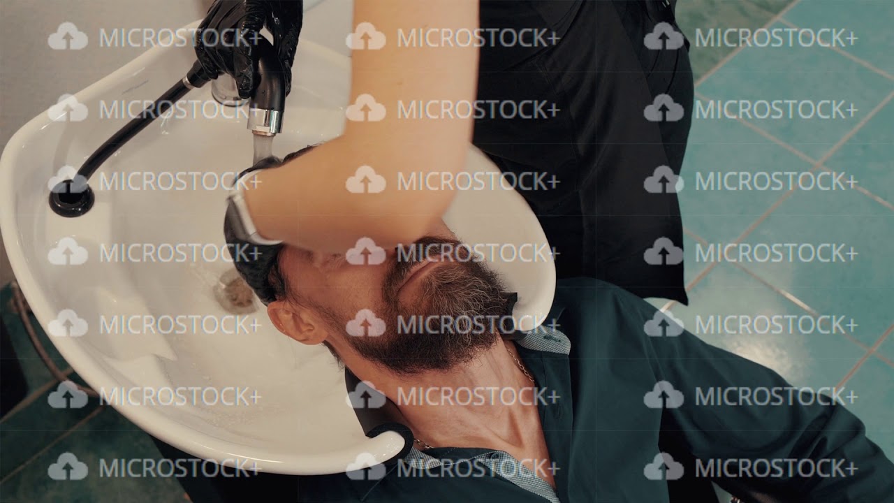 Cropped shot of barber washing hair to male client in hair salon