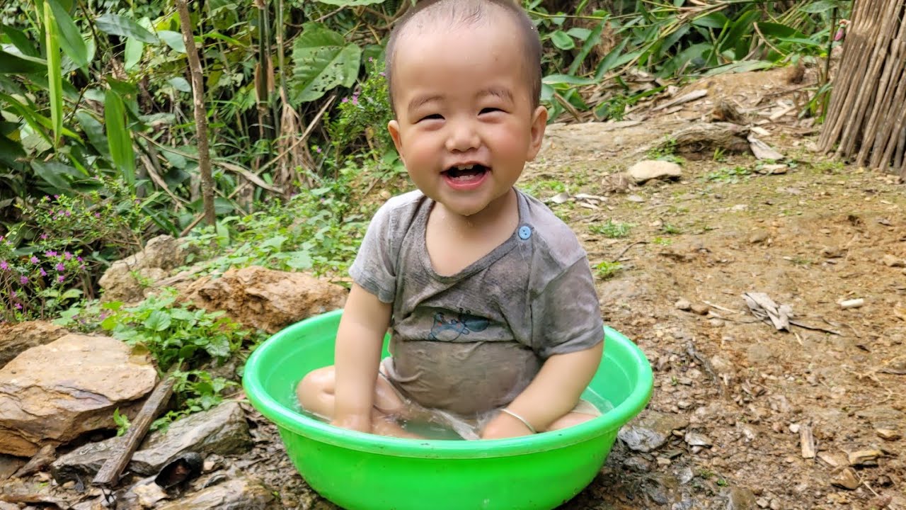 The woman is bathing the baby.