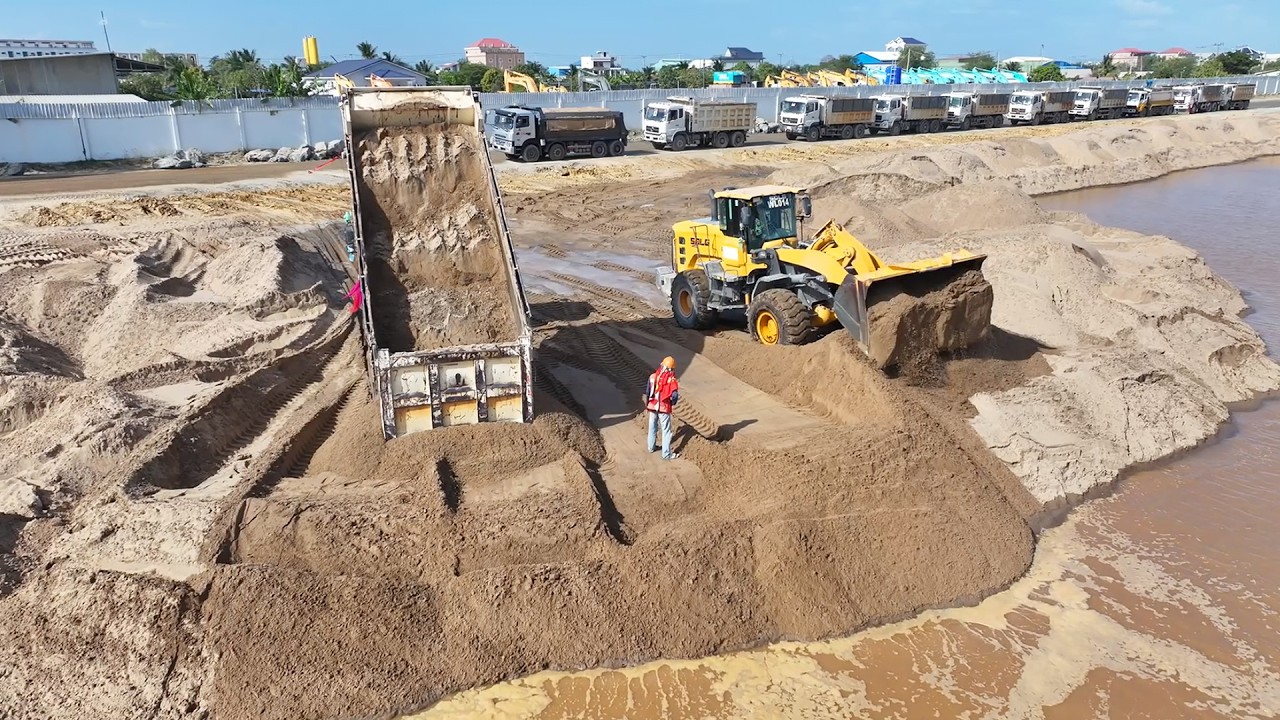 good job!!wheel loader SDLG push sand in water with shacman truck delivery sand filling land