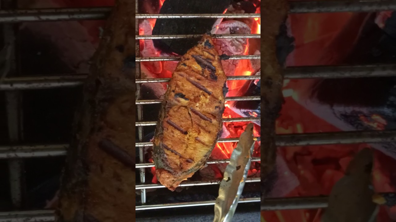 Fish fry in banana leaf on charcoal grill 