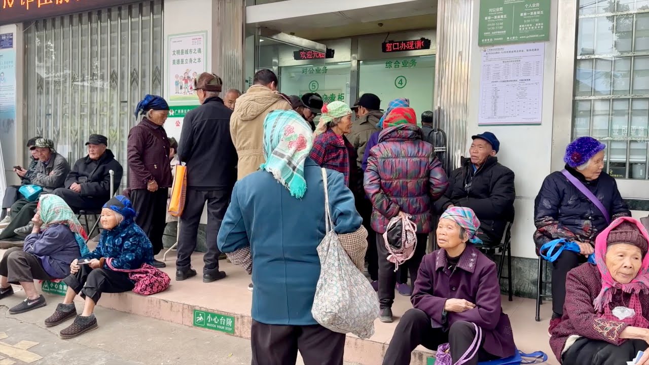 银行里挤满取钱的老人，银行利息太低了。天气寒冷，老人烧废材烤火取暖