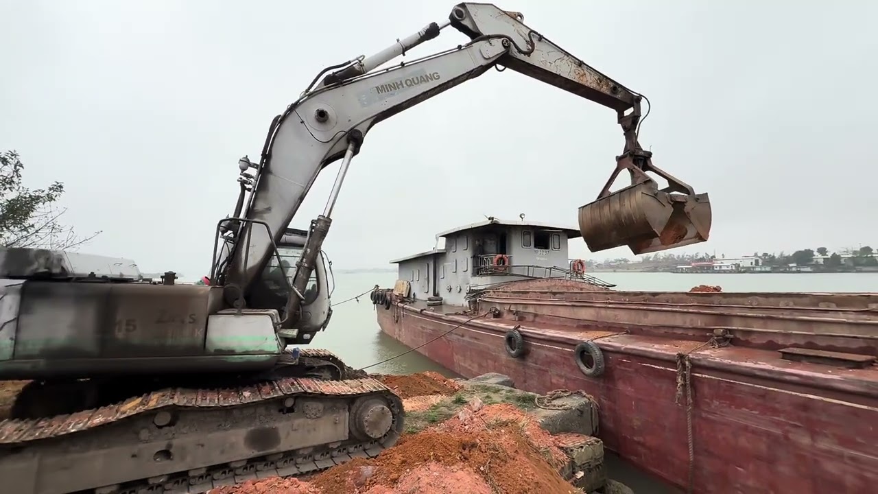 Loading dirt onto a barge by crane 