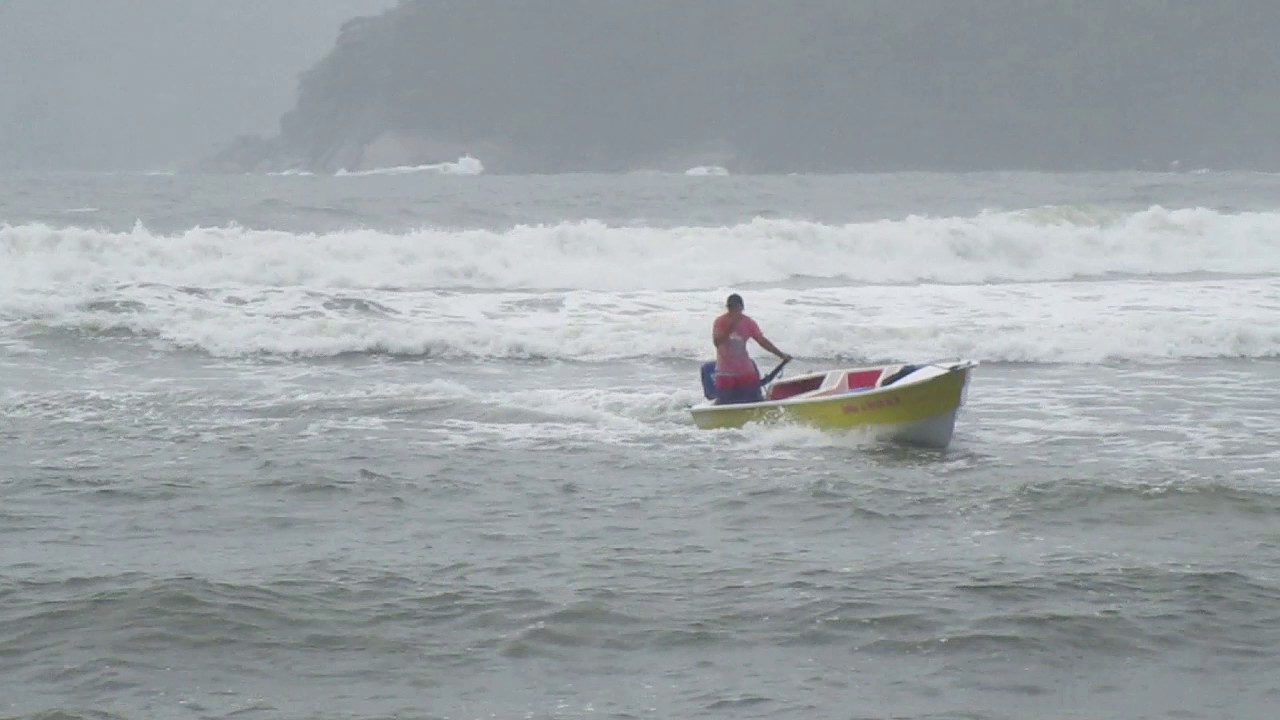 Barco tentando sair da praia de Martin Sá num dia de mar agitado