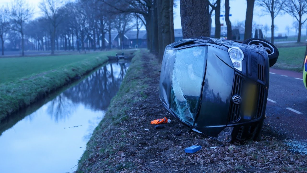 Auto botst tegen boom en belandt op zijkant