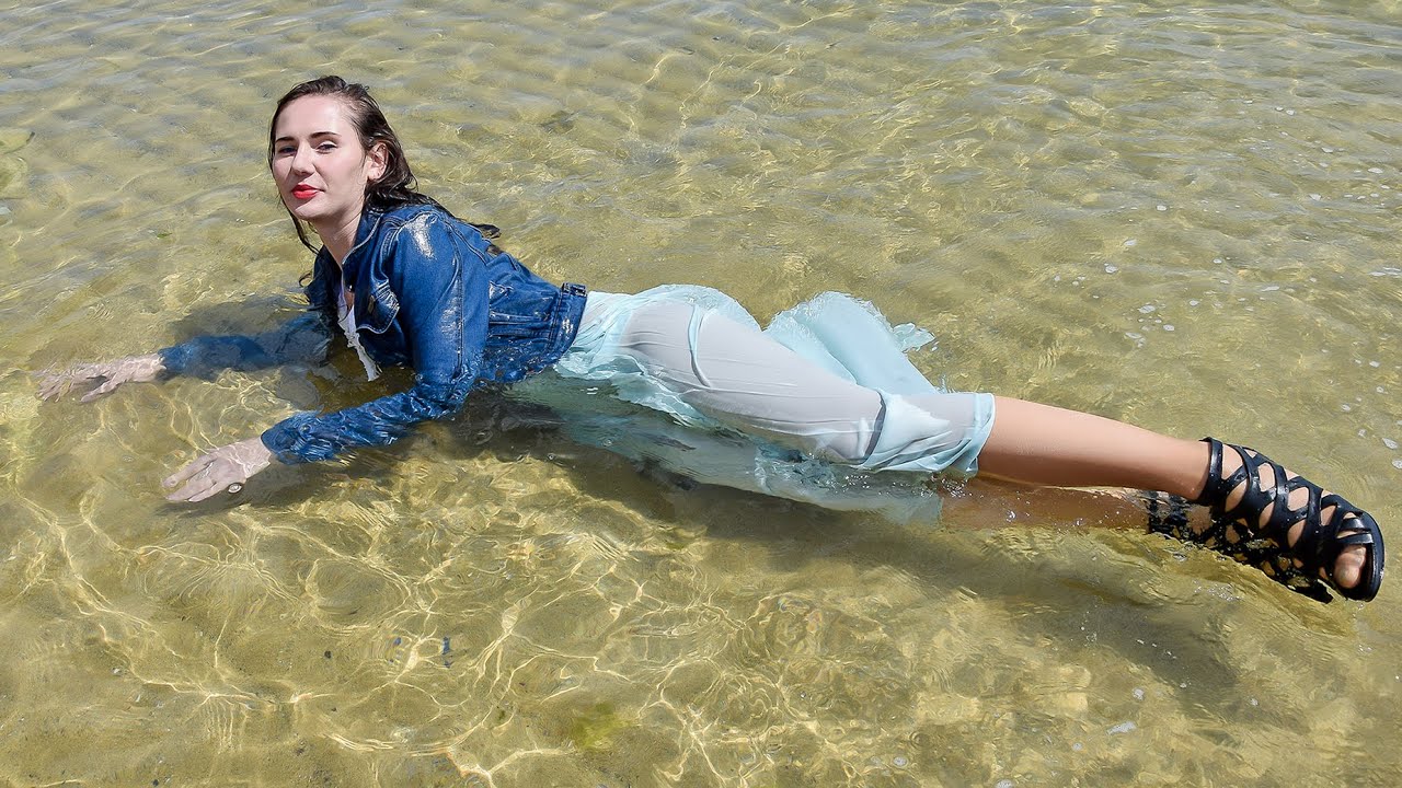 DON'T MISS! GORGEOUS GIRL IN A WET DENIM JACKET AND WET DRESS POSE BRIGHTLY ON THE BEACH BY THE SEA