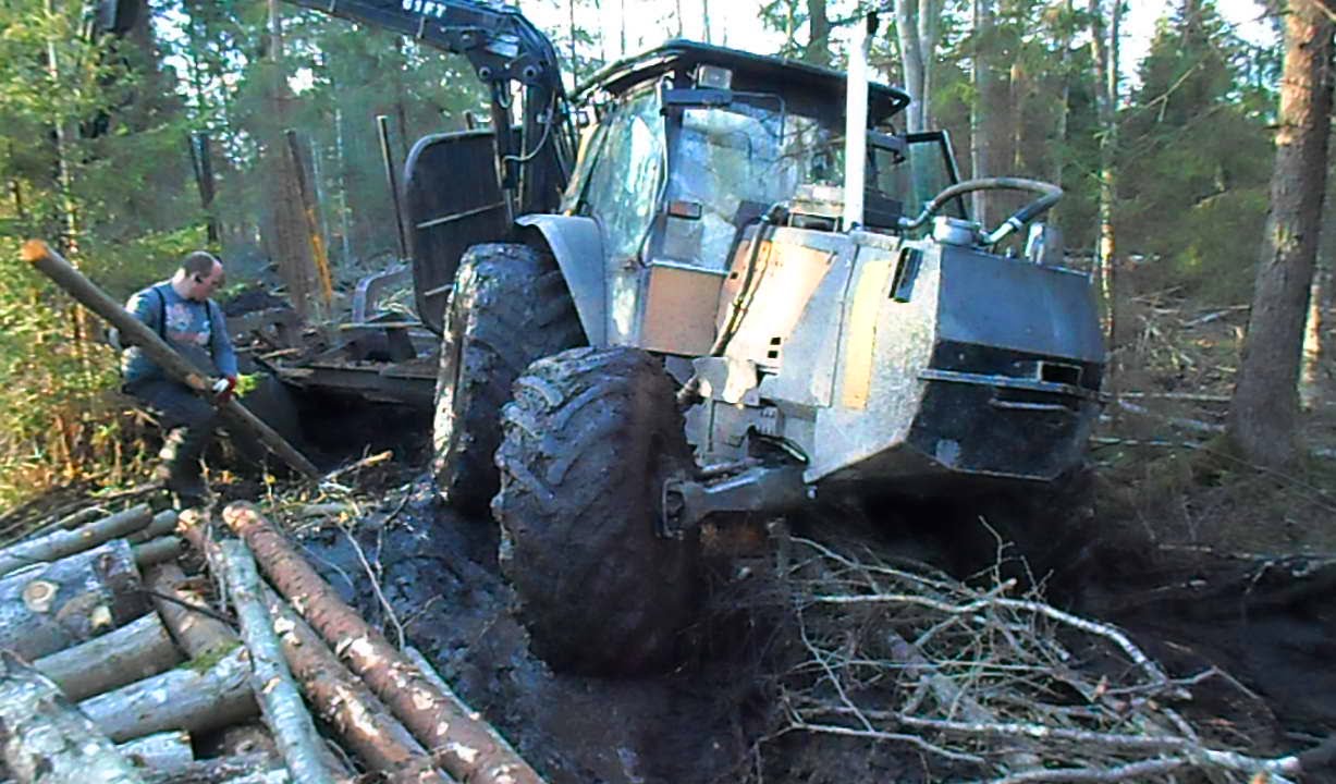 Valtra forestry tractor stuck in mud with big trailer in wet forest