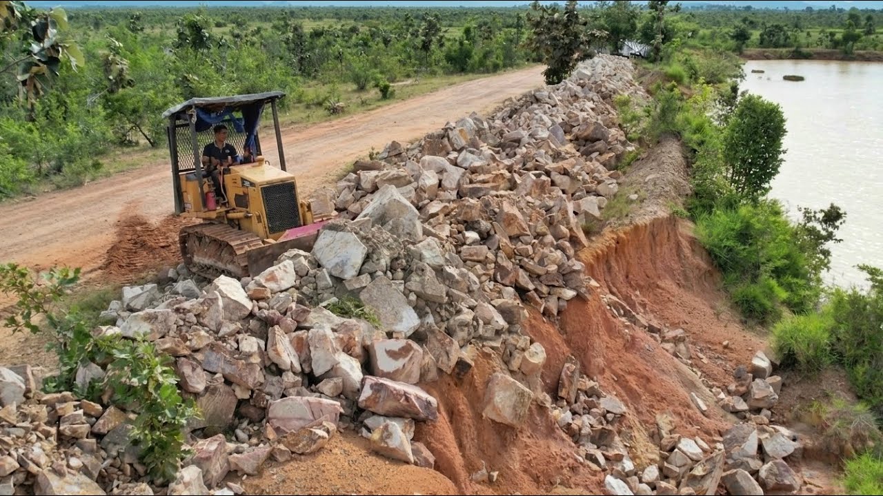 Clearing large rocks to drop down along the sidewalk of a deep pond
