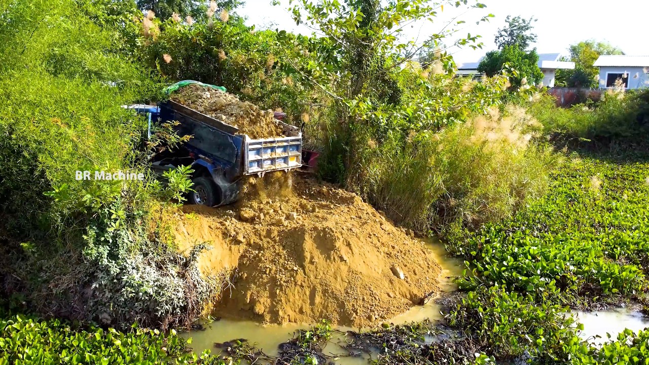 BULLDOZER pushing stone into the lake for build the new road DUMP TRUCK UNLOAD the stone
