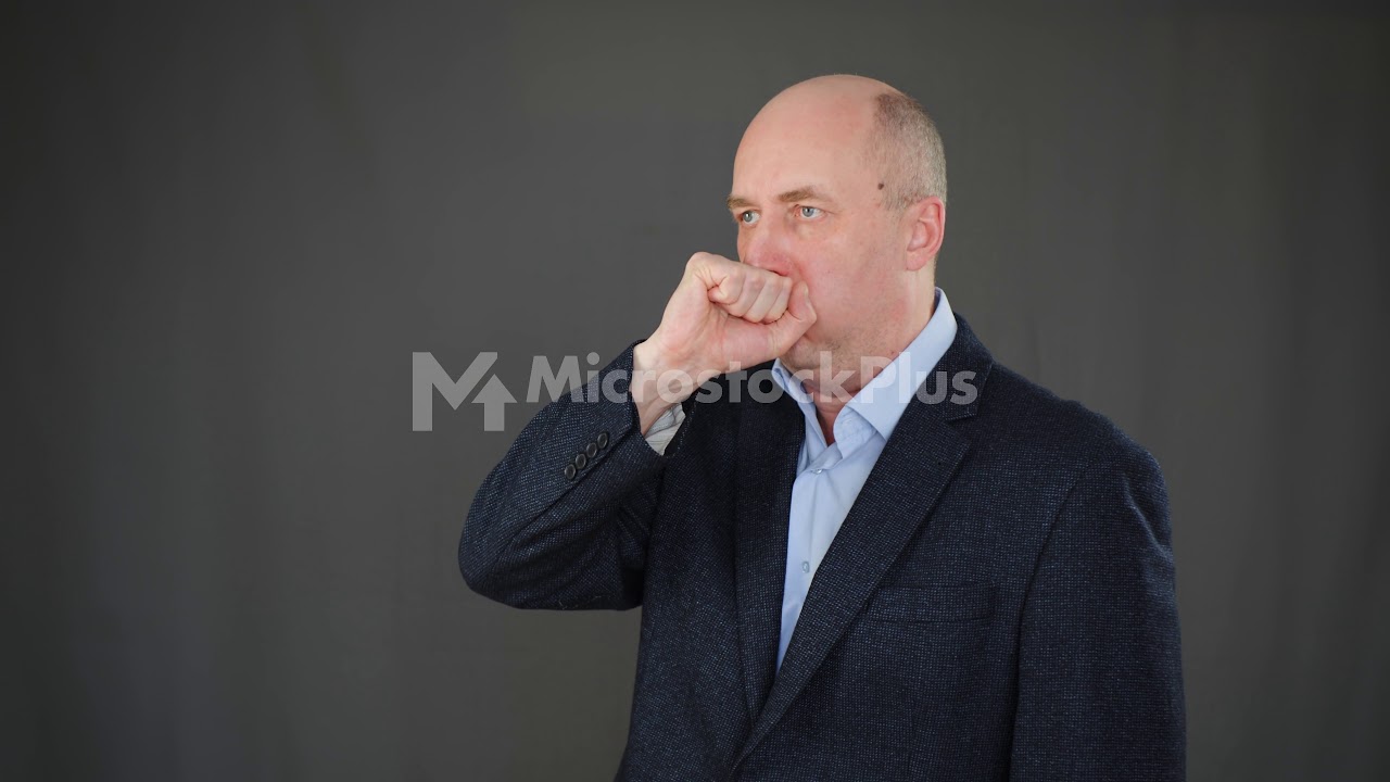 Sick man coughing into fist on black background in studio. Cold man coughing into fist while flu