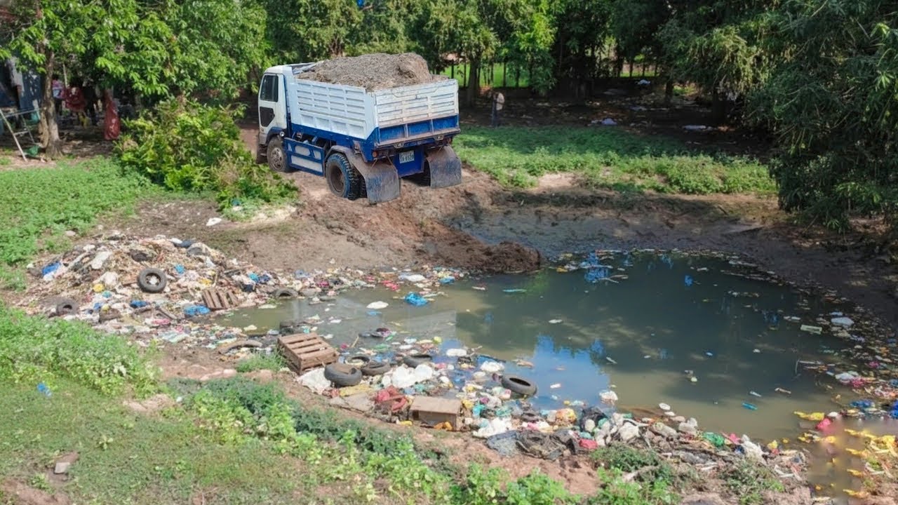 Delete the pond behind house to operation building new house by skill dozer pushing with dump truck