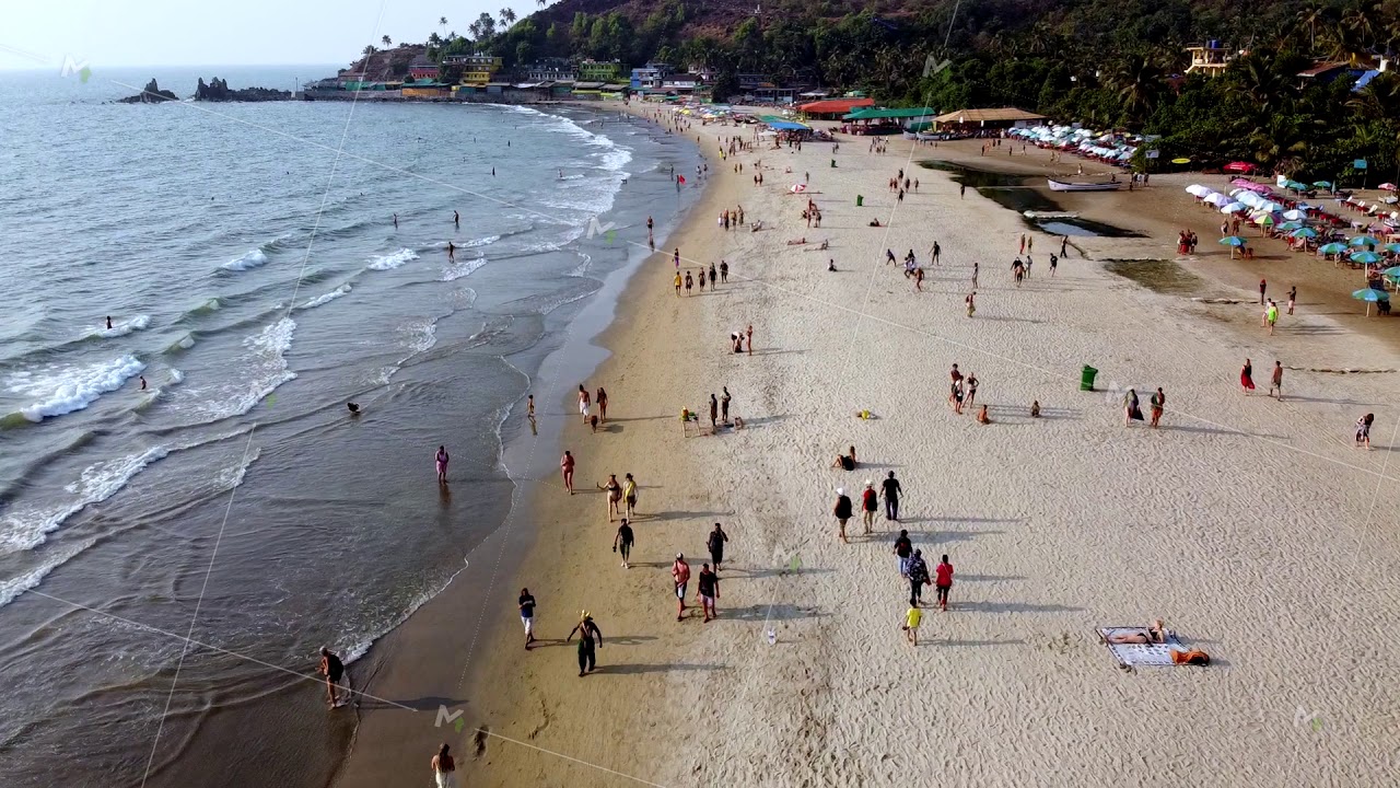 Arambol Goa India drone fly over a sunset beach, people walk along the sunset beach