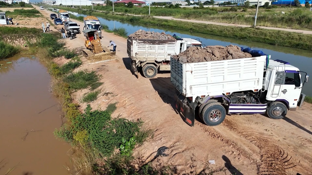 Great Land filling action by bulldozers & dump trucks working in perfect coordination soil and stone
