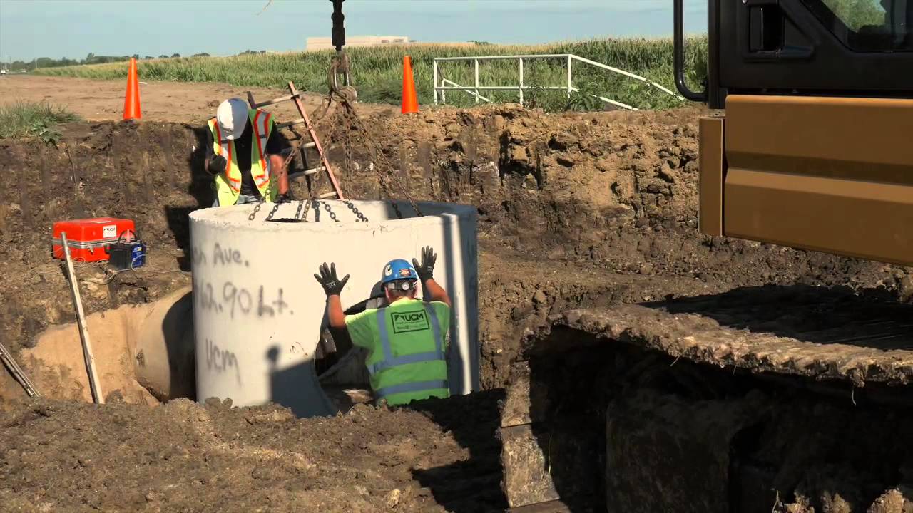 Cat&reg; 325F Hydraulic Excavator at Work Lifting and Setting a Manhole