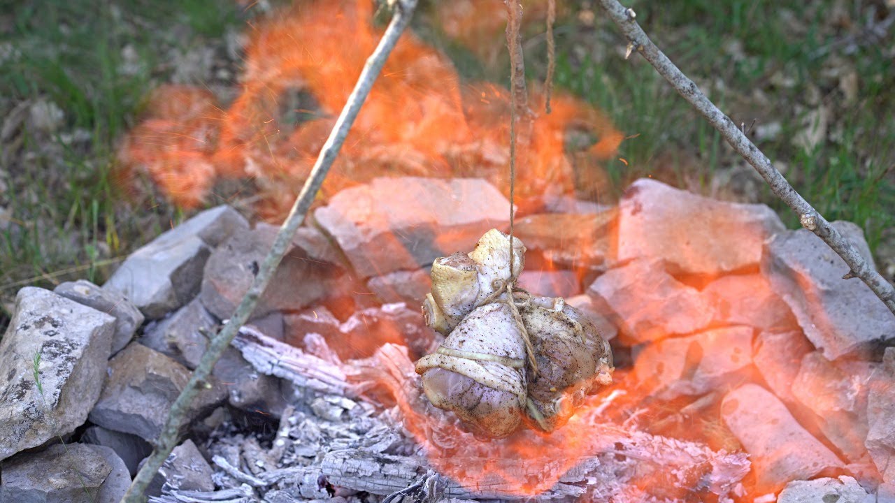 Hähnchen über offenem feuer grillen. Kochen im Wald