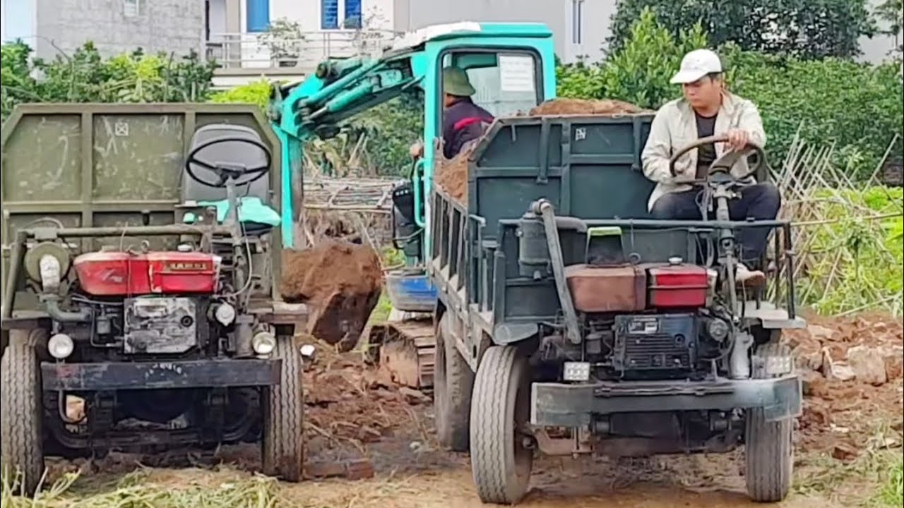 Excavator scoops soil onto homemade tractor