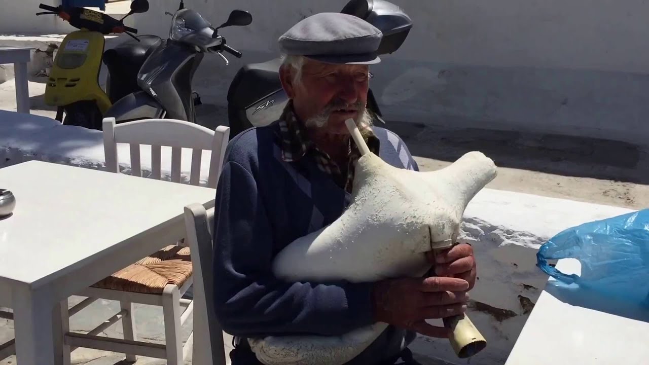 Mykonos Greece. Greek Fisherman plays a wind instrument made from sheep skin.