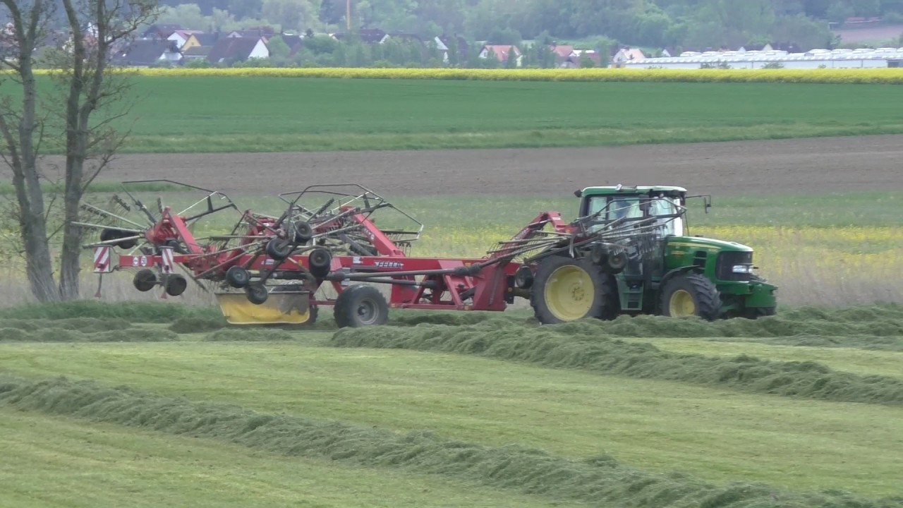 John Deere Traktor mit Fella Vierkreisel   Mittelschwadablage beim Schwaden von ersten Schnitt am 15