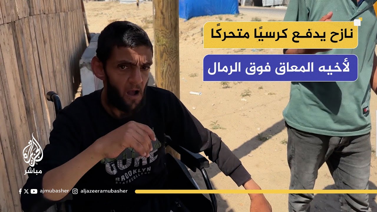 نازح يدفع كرسيًا متحركًا لأخيه المعاق فوق الرمال، بحثًا عن المساعدة