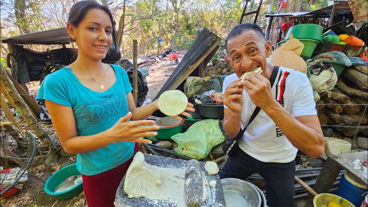 Salvadoreña haciendo tortillas de maíz amano en comal de barro
