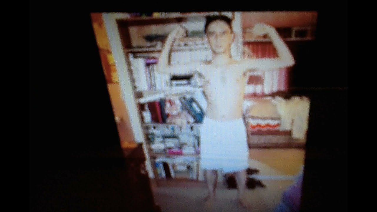 Shirtless Barefoot Minimalist Male nerd shows off his book shelf