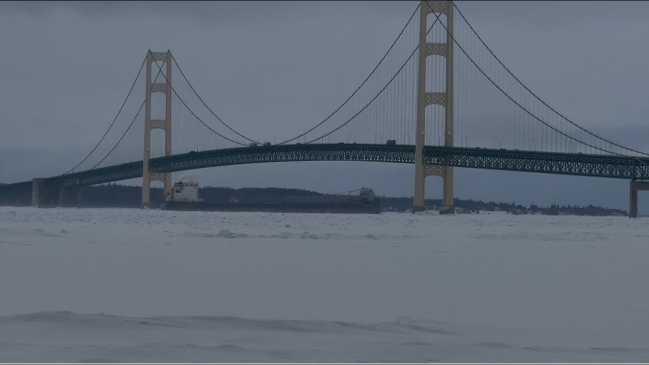 Freighter cutting through ice in Straits of Mackinac under the Bridge