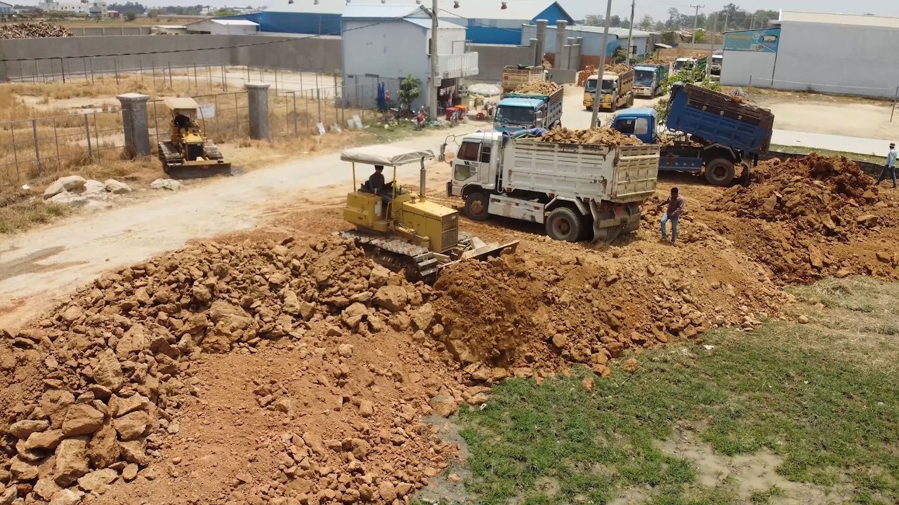 Land Filling Operation Begins!! Teamwork skilled dozer operator and dump truck drivers moving soil.