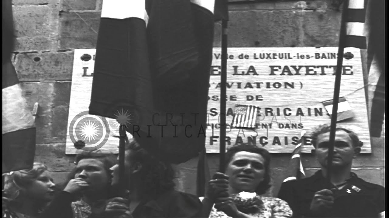 French civilians stand holding flags and cheer in Luxeuil-Les-Bains, France. HD Stock Footage