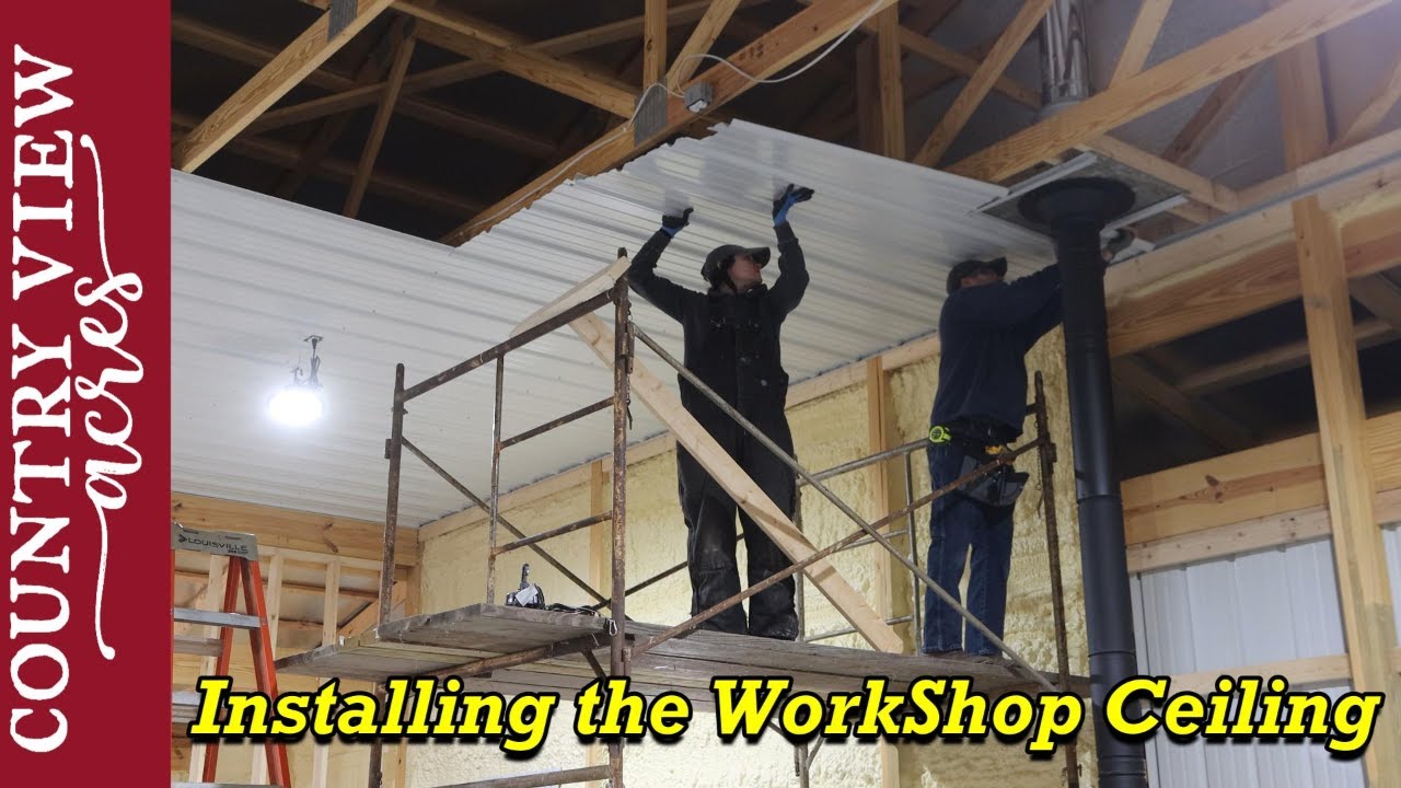 Using a rolling scaffold to install the 14 foot high metal Ceiling in the new workshop.