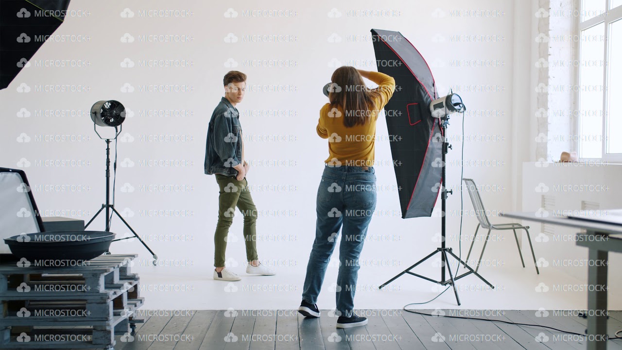 Female photographer showing body positions to male model working in studio