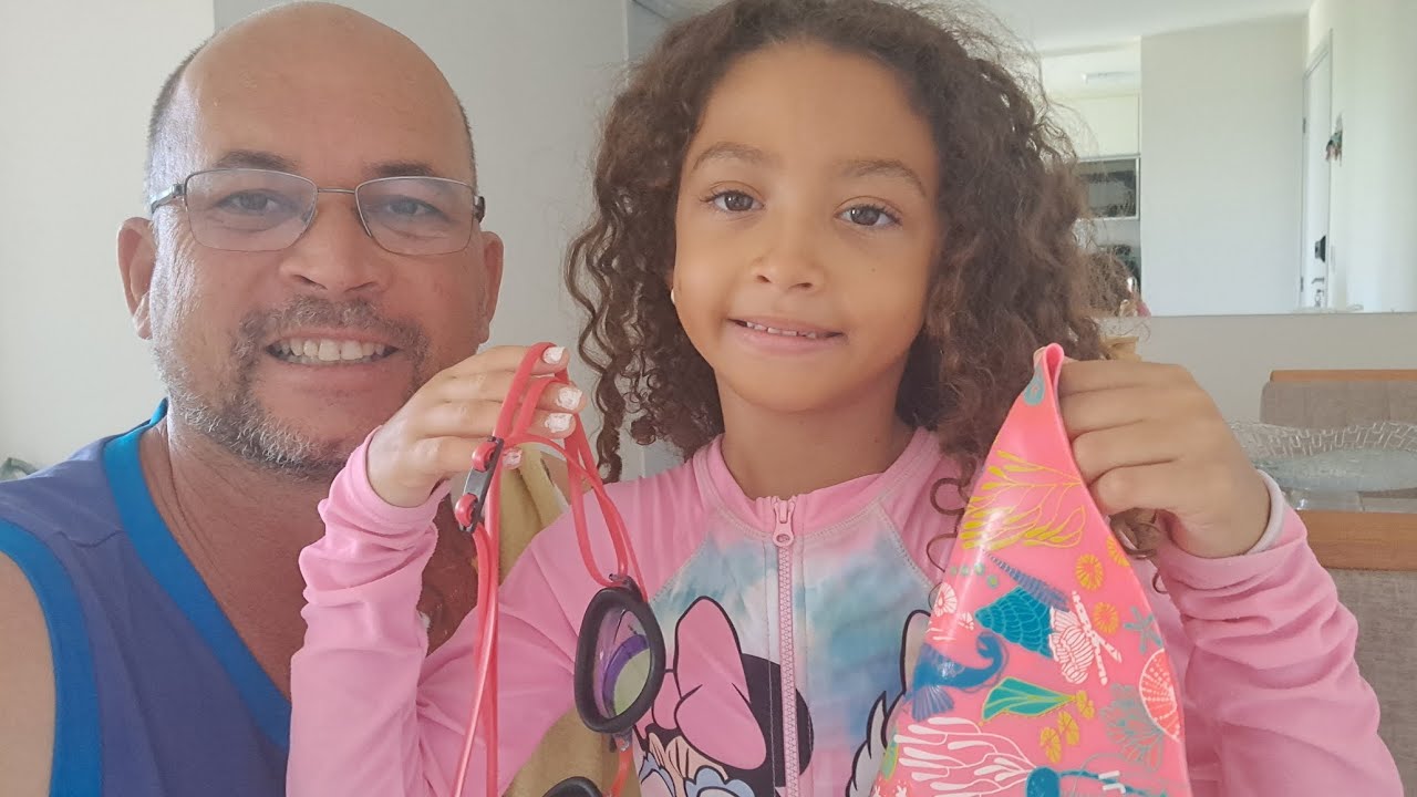O papai vai ensinar a Lorena a nadar na piscina com banho de mangueira. 