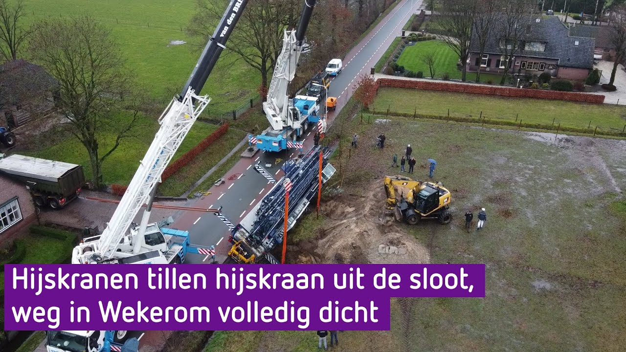 Twee hijskranen halen grote hijskraan uit de sloot