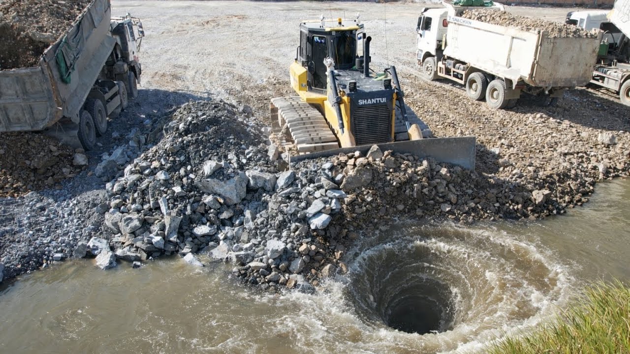 Interesting SHANTUI Bulldozer pushing landfill in flooding area with Dump Trucks loading soils 
