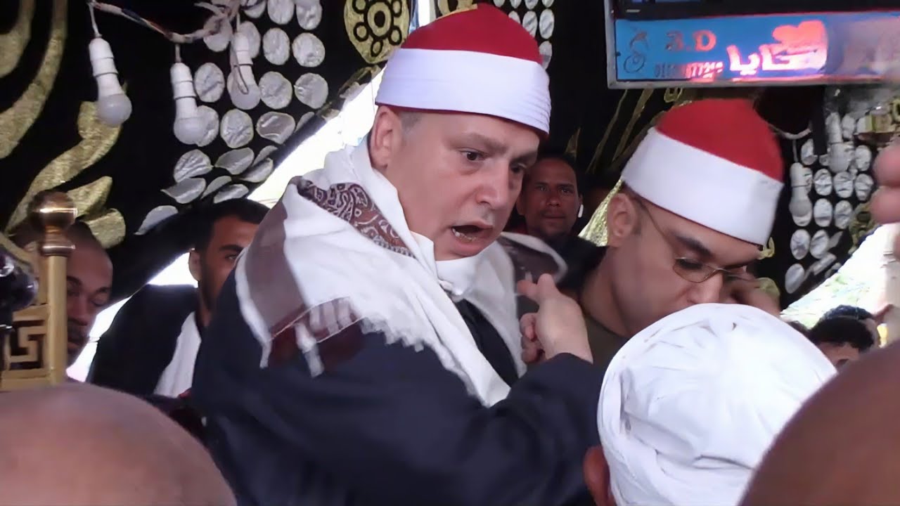 الشيخ حجاج  الهنداوي ينزل من علي دكة التلاوة ويطلب من الشيخ فتحي موسي الصعود بسبب ما حدث في العزاء