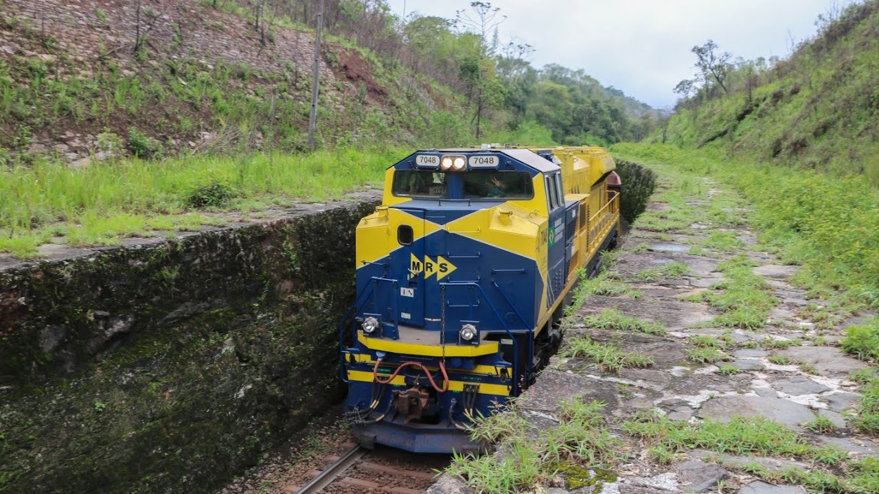 Locomotiva EMD SD70LC sozinha puxando mais de 80 vagões passando por centímetros do paredão de pedra