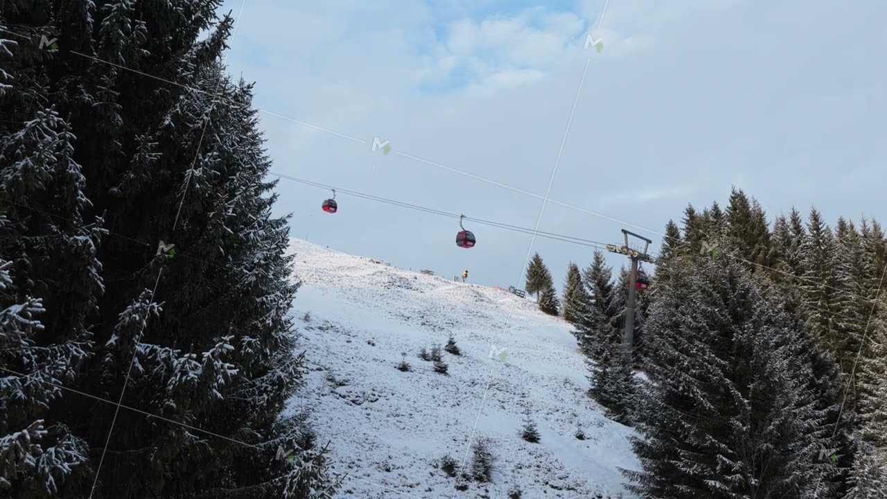 Elevated static view of ski lift gondola transporting people up a snowy mountain slope surrounded by