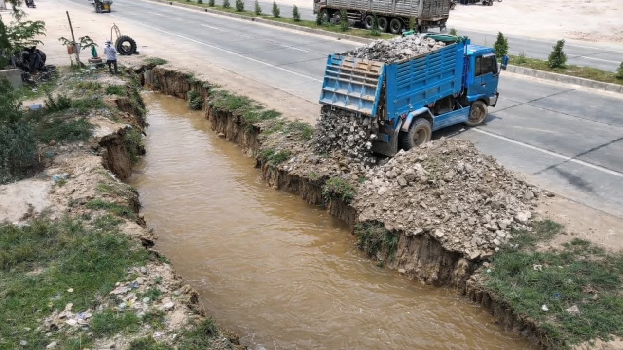 Small Dump Trucks Unloading Rock Filling Land With Small Dozer 