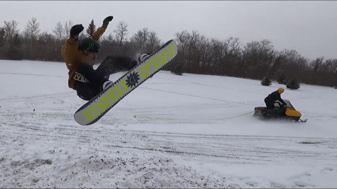 Sending a huge jump behind the snowmobile!