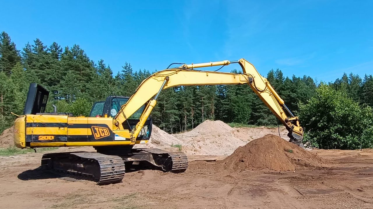 Loading soil into dump trucks with excavator JCB 200
