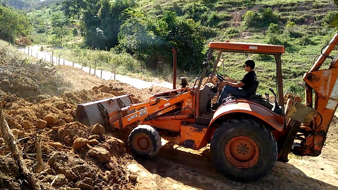 Retroescavadeira cortando e espalhando terra