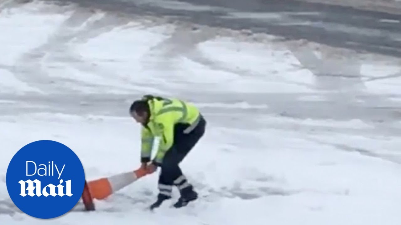 Airport worker tries to clear snow with traffic cone - Daily Mail