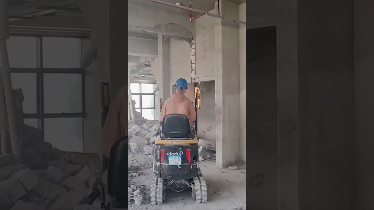 Mini excavator vibratory hammer demolishes interior wall