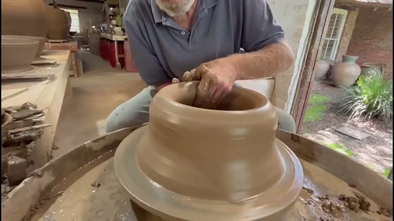 Digby Hoets throwing base section of one of a group of six pots