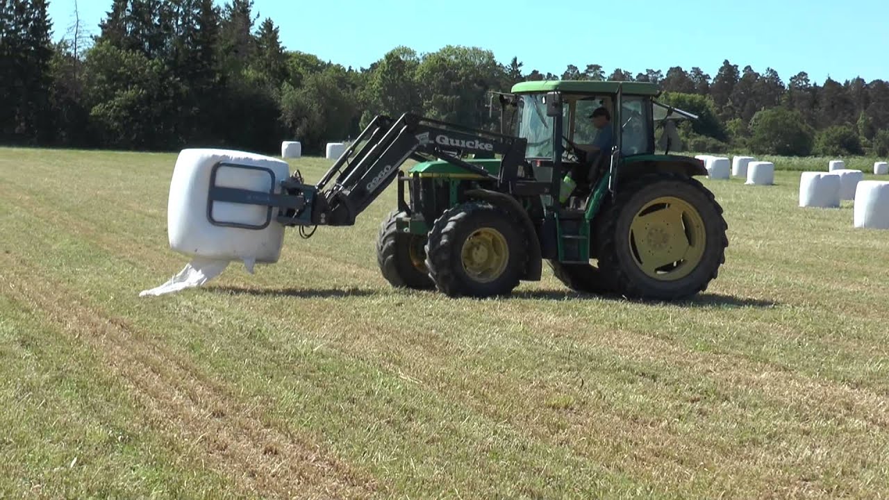 John Deere 6310 tractor download large bales and loaded on a trailer 2013