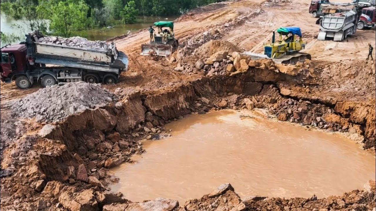 Komatsu Dozers Pushing Rock Filling Land With Many 25T Dump Trucks